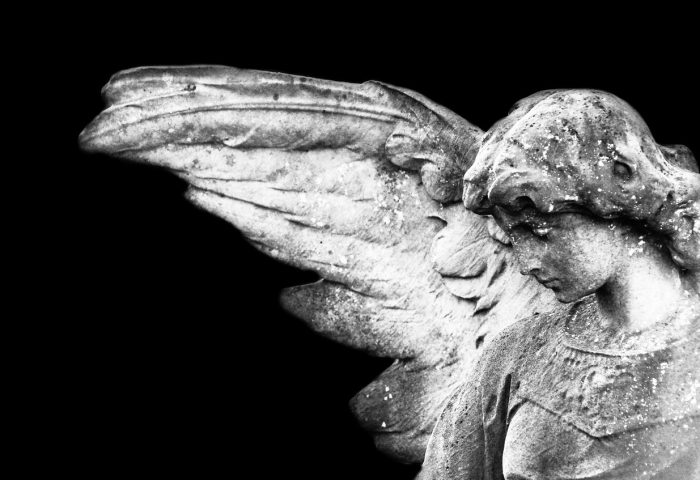 Estatua de ángel angelical con fondo negro.