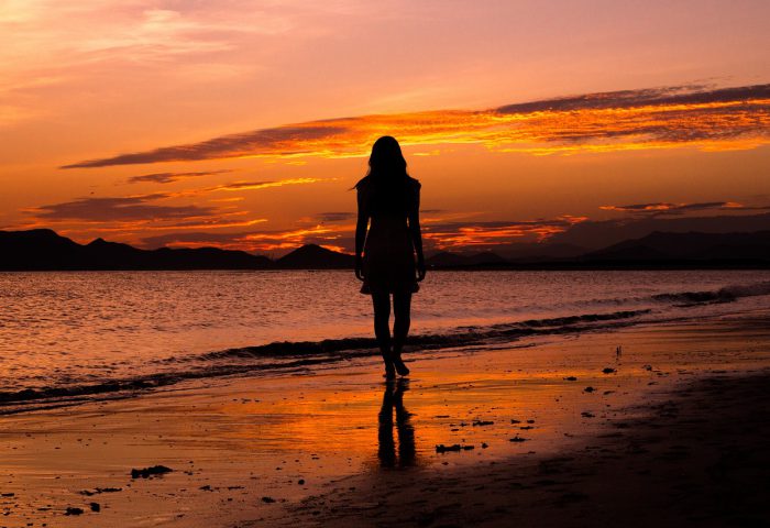 Atardecer con silueta de mujer frente al mar.